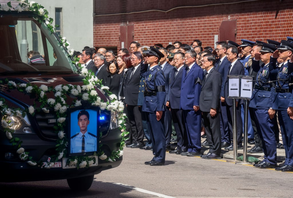 Chief Executive John Lee and other senior officials stand in silence as the hearse departs Universal Funeral Parlour for Cheung Sha Wan Police Station. Photo: Jonathan Wong