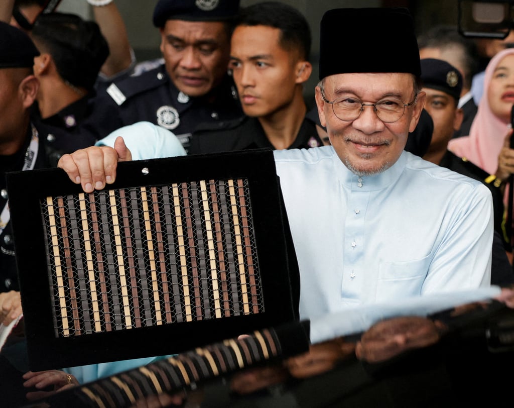 Malaysia’s Prime Minister and Finance Minister Anwar Ibrahim holds up the 2027 national budget document as he departs for parliament to table the budget on October 9. Photo: Reuters