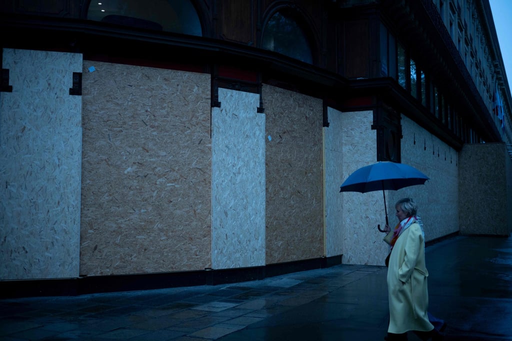 A woman walks past a closed store protected with wooden panels in Paris on Saturday. Photo: AFP A woman walks past a closed store protected with wooden panels in Paris on Saturday. Photo: AFP