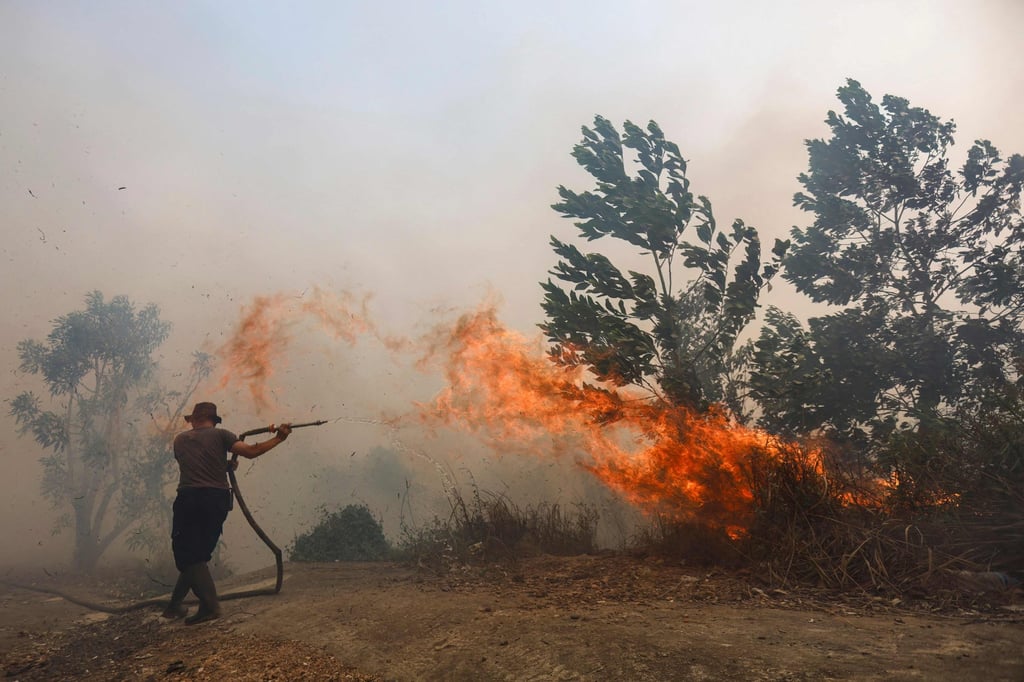 A firefighter battles a fast-moving brush fire amid heavy smoke in South Kalimantan, Indonesia. Photo: AFP A firefighter battles a fast-moving brush fire amid heavy smoke in South Kalimantan, Indonesia. Photo: AFP