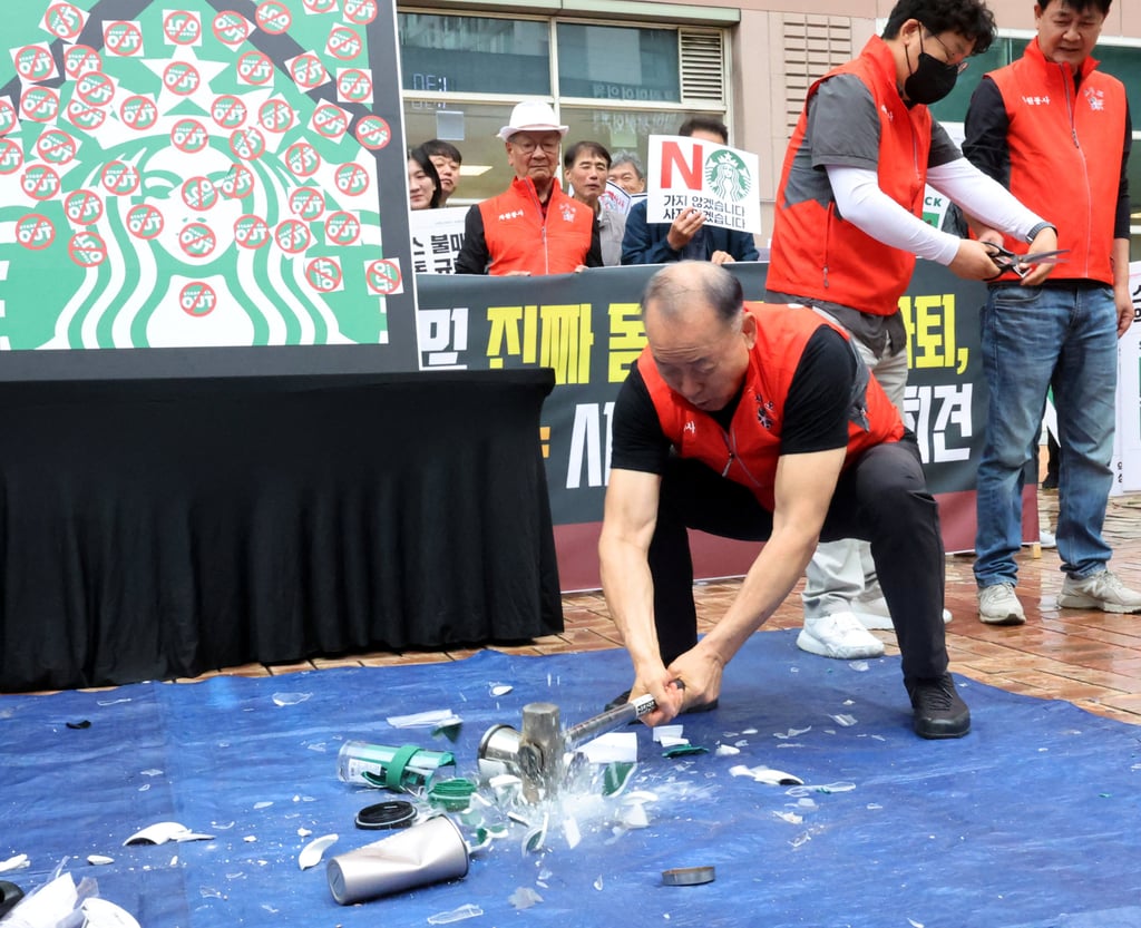 An activist smashes Starbucks tumblers and mugs during a protest against Starbucks’ Tank Day campaign on May 21. Photo: Yonhap / Reuters