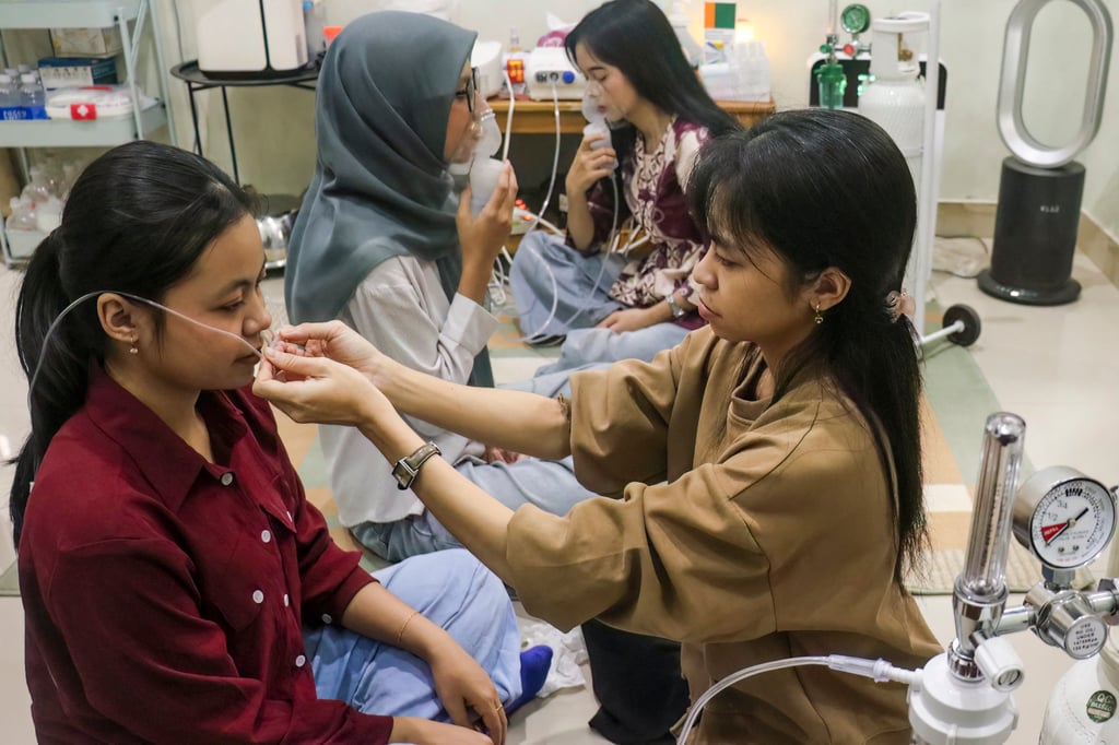 A volunteer helps a woman with a nasal oxygen cannula at a shelter run by the Central Kalimantan Forest and Land Fire Smoke Response Coalition in Palangka Raya on Monday. Photo: AFP A volunteer helps a woman with a nasal oxygen cannula at a shelter run by the Central Kalimantan Forest and Land Fire Smoke Response Coalition in Palangka Raya on Monday. Photo: AFP