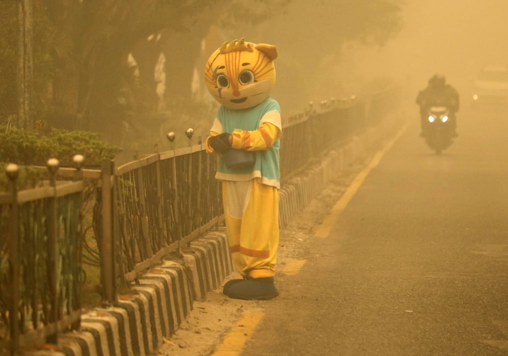 A busker in a tiger costume stands at a traffic light amid the thick haze in Palangka Raya, Central Kalimantan, on Sunday. Photo: AFP A busker in a tiger costume stands at a traffic light amid the thick haze in Palangka Raya, Central Kalimantan, on Sunday. Photo: AFP