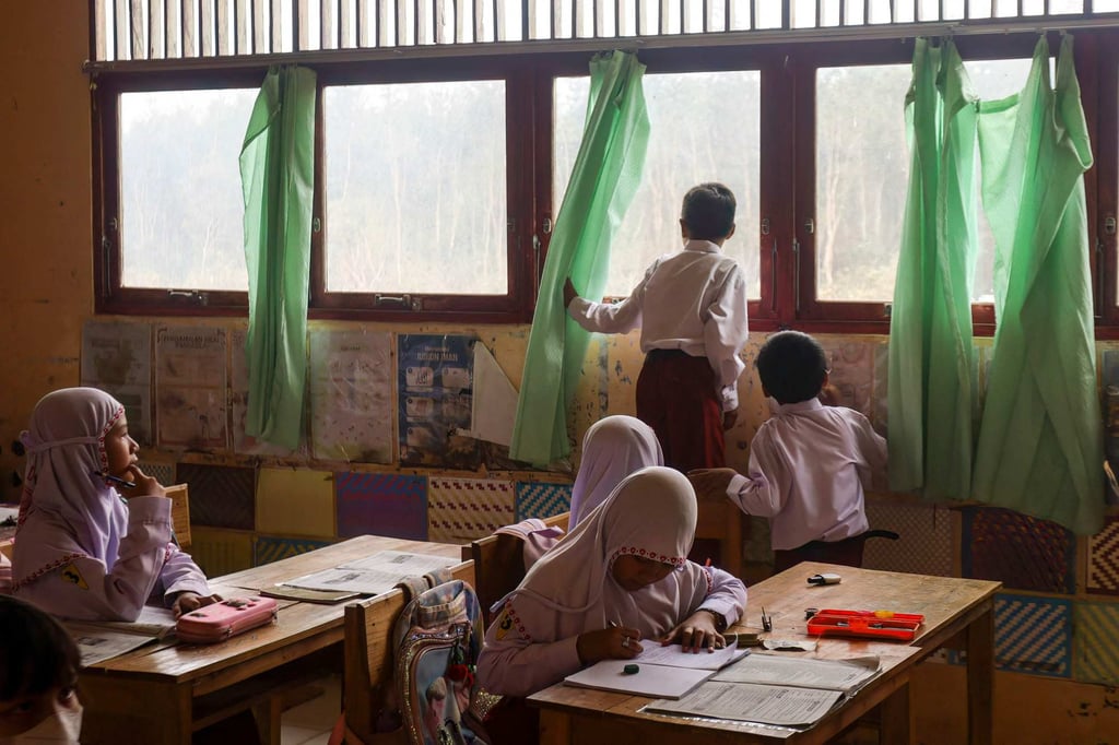 An elementary pupil in South Kalimantan, Indonesia, watches smoke from an encroaching land fire on Wednesday, before classes were cancelled due to hazardous regional haze. Photo: AFP