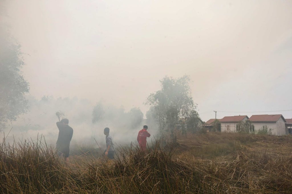 A child walks among volunteers struggling to extinguish a land fire that reignited behind an elementary school at Alalak village in South Kalimantan, Indonesia, on Wednesday. Photo: AFP A child walks among volunteers struggling to extinguish a land fire that reignited behind an elementary school at Alalak village in South Kalimantan, Indonesia, on Wednesday. Photo: AFP