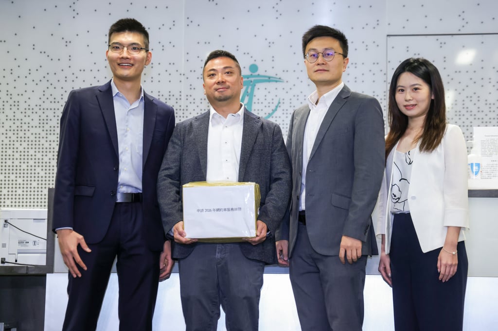 Representatives of ride-hailing platform DiDi pose with their licence application documents at the Transport Department’s headquarters in the West Kowloon Government Offices in Yau Ma Tei. Photo: Silvia Siu