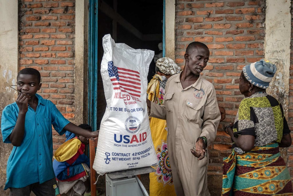 A Burundian government official speaks to newly arrived Congolese refugees while weighing a sack of rice from the final batches delivered by the now-dismantled USAID in May 2025. Photo: AFP A Burundian government official speaks to newly arrived Congolese refugees while weighing a sack of rice from the final batches delivered by the now-dismantled USAID in May 2025. Photo: AFP