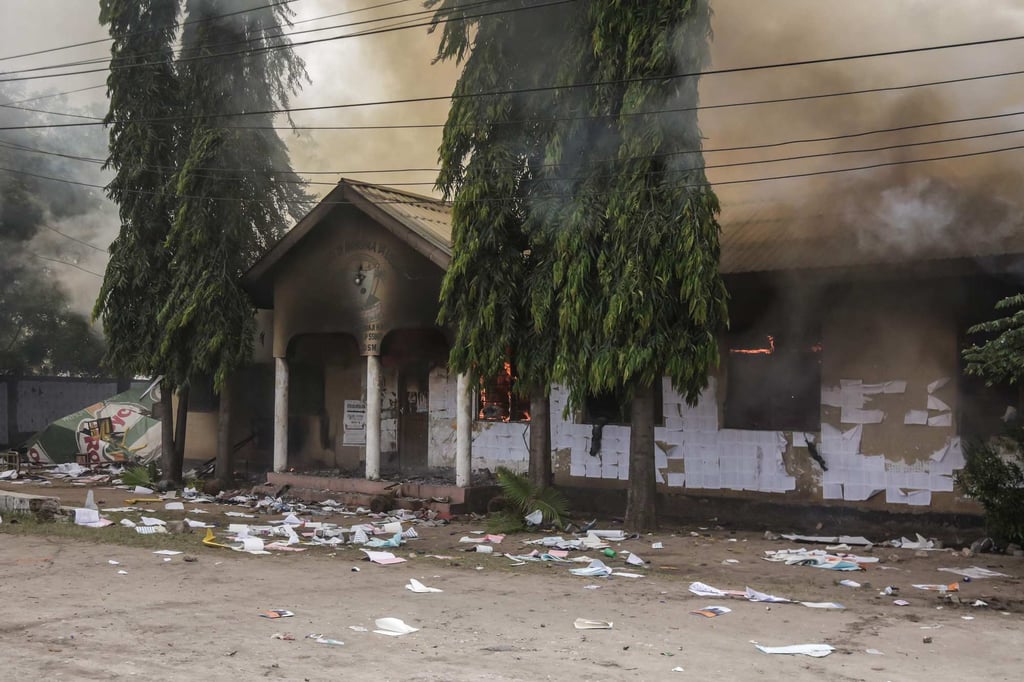 Smoke and flames can be seen at a polling station in Dar es Salaam in Tanzania in October 2025 during presidential elections. Security forces were accused of killing thousands of protesters. Photo: AFP