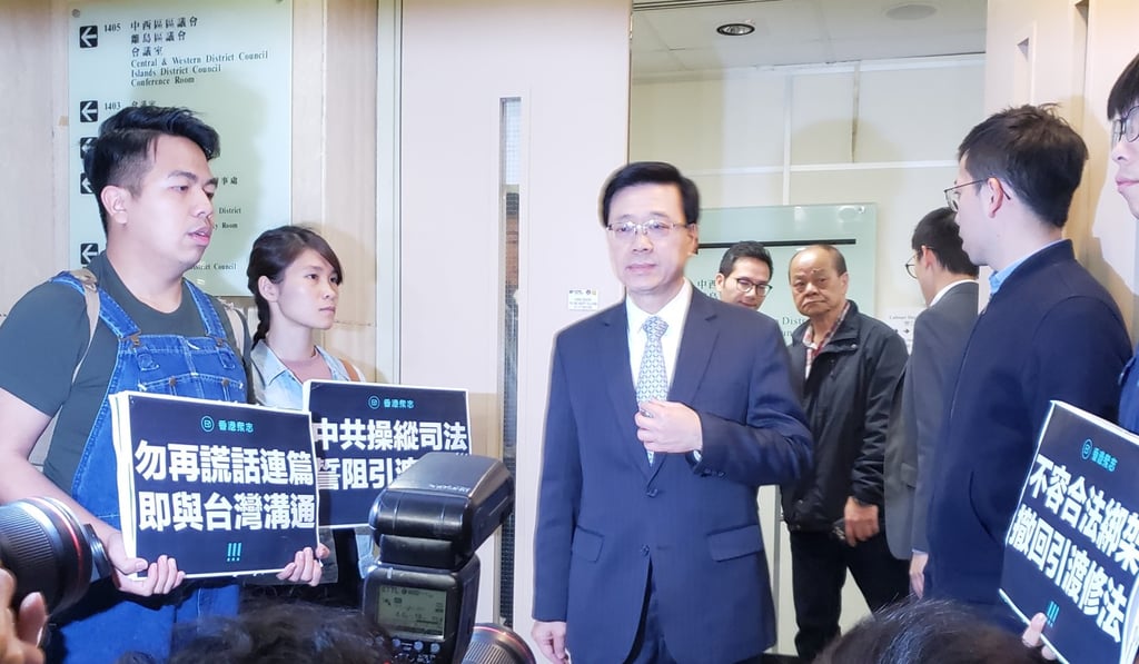 Members of the political party Demosisto protest to Secretary for Security John Lee (centre) over the proposed extradition amendment at Central and Western District Council on Wednesday. Photo: Sue Su