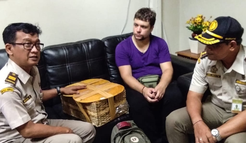 Officials with detained Russian national Andrei Zhestkov (centre), who was accused of smuggling an orangutan. Photo: Natural Resources Conservation Agency of Bali/AFP Officials with detained Russian national Andrei Zhestkov (centre), who was accused of smuggling an orangutan. Photo: Natural Resources Conservation Agency of Bali/AFP