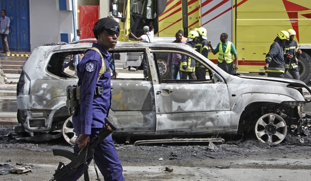 A member of security forces walks past the burned-out vehicle after a bomb planted in it exploded in Mogadishu. Photo: AP Photo