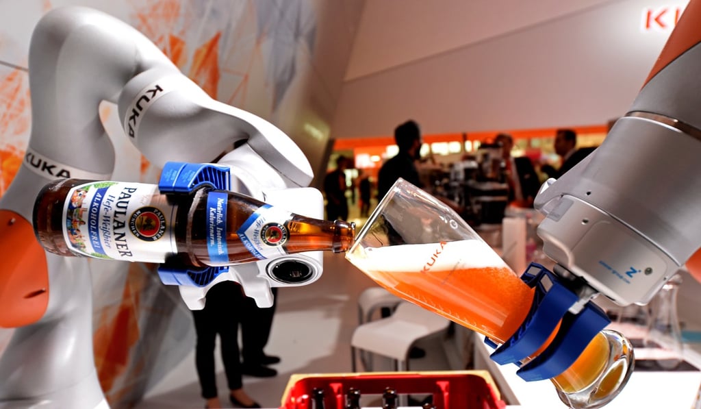 A robotic arm fills a glass with Bavarian Weiss beer at the booth of German company Kuka at the world's biggest industrial fair,