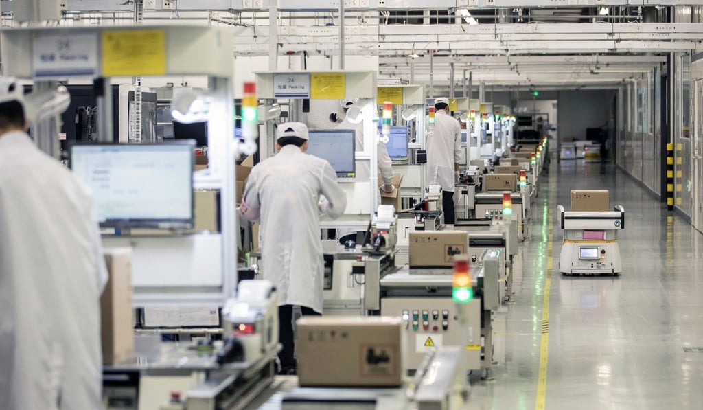 A robot, right, passes employees working on a mobile phone assembly line at a Huawei Technologies Co. production base in Dongguan, China. Photor: Qilai Shen / Bloomberg