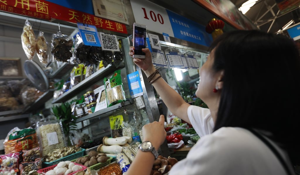 A woman scans an Alipay QR code to make a payment via her mobile phone in a market in Beijing, China. How Hwee Young/EPA