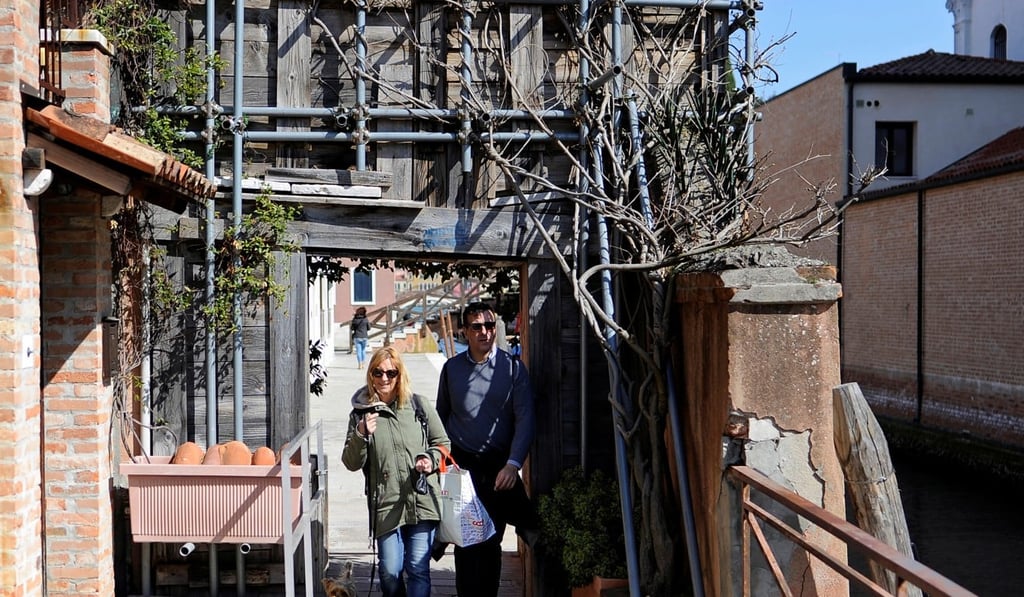 Patrizia Zaniol and Nicola Ussardi, who live in illegally occupied flats, walk through the only entrance by land to the Casette neighbourhood where about 20 flats are illegally occupied. Photo: Reuters