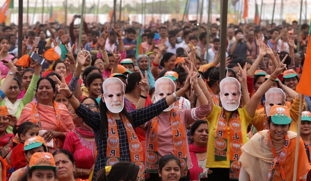 Indian people wearing Prime Minister Narendra Modi masks cheer as they attend his election campaign rally. Photo: EPA