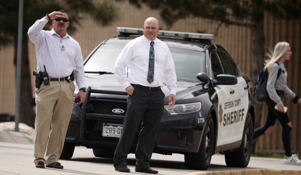 Columbine High School principal Scott Christy (right) joins an officer in watching as students leave the school late Tuesday, April 16, 2019. Photo: AP