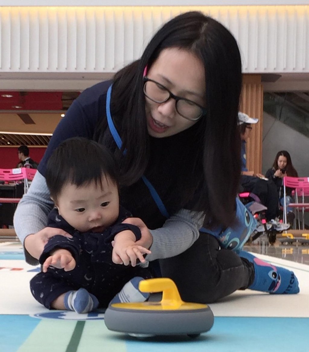 A six-month-old baby girl tries her hand at FloorCurling supported by her mother. A six-month-old baby girl tries her hand at FloorCurling supported by her mother.