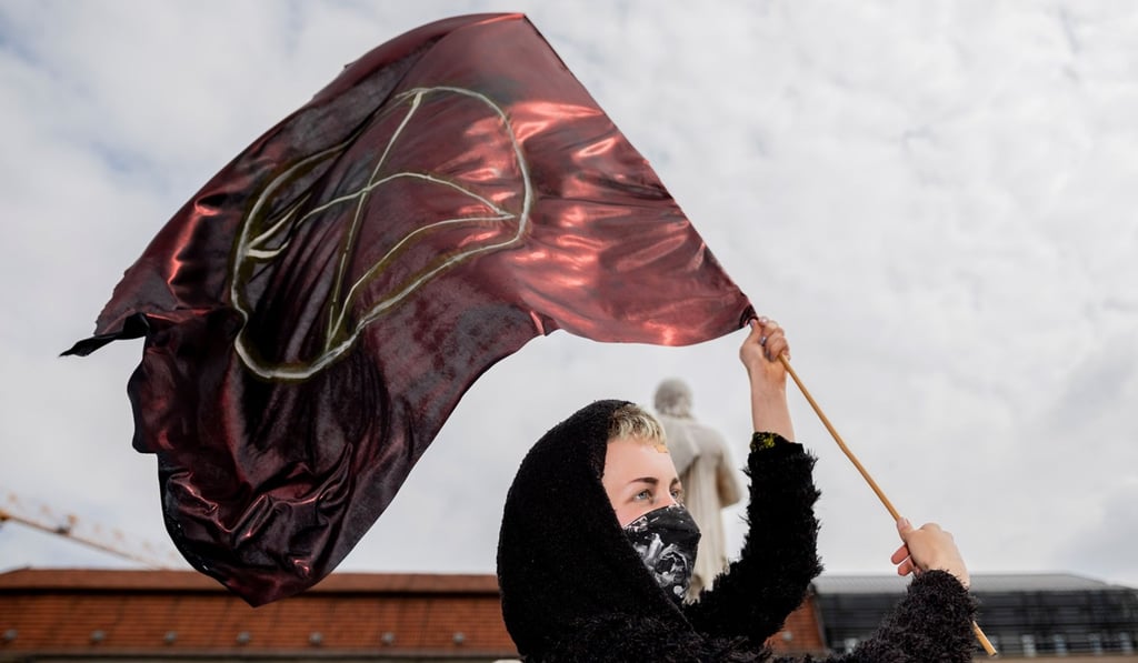 An Extinction Rebellion climate change activist holds a flag with their symbol during a protest at the Gendarmenmarkt square in Berlin. Photo: AFP