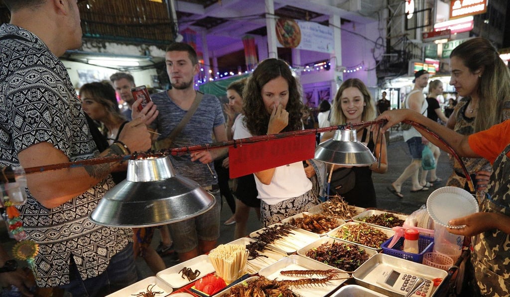 Tourists look at food for sale at a street food stall on Khao San road, in Bangkok. Photo: EPA
