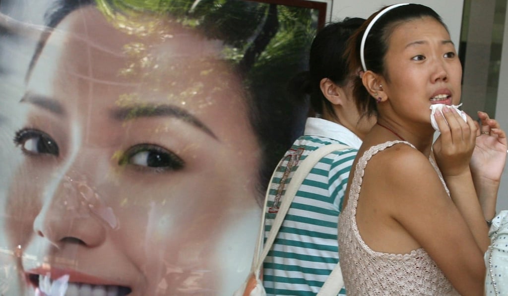 A woman walks past an advertisement for a skin whitening product in Shanghai in August 2006. Photo: AFP