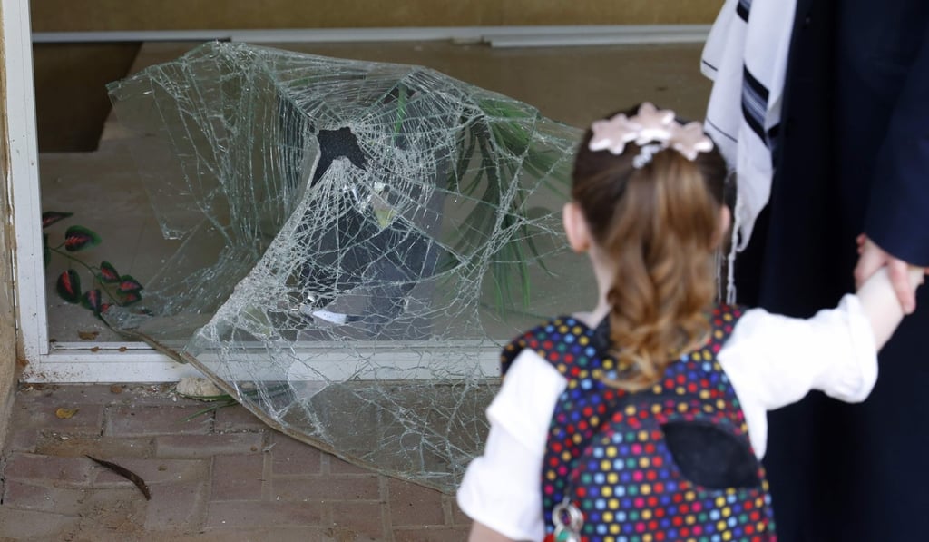 An Israeli child looks at shattered glass at the entrance to her apartment building. Photo: AFP