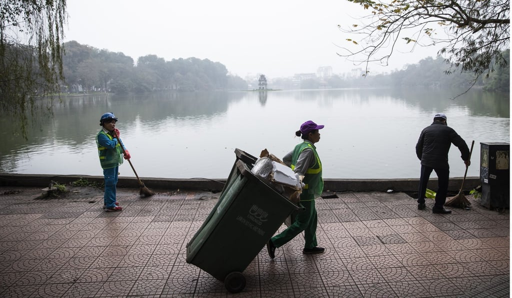 Workers clean a footpath around the Hoan Kiem Lake in Hanoi. Photo: Bloomberg