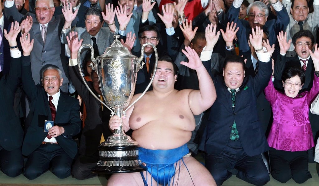 Ozeki, or champion, Kotoshogiku (centre) holds the Emperor's Cup trophy as he celebrates following his victory in the New Year Grand Sumo tournament in January 2016. Photo: AFP