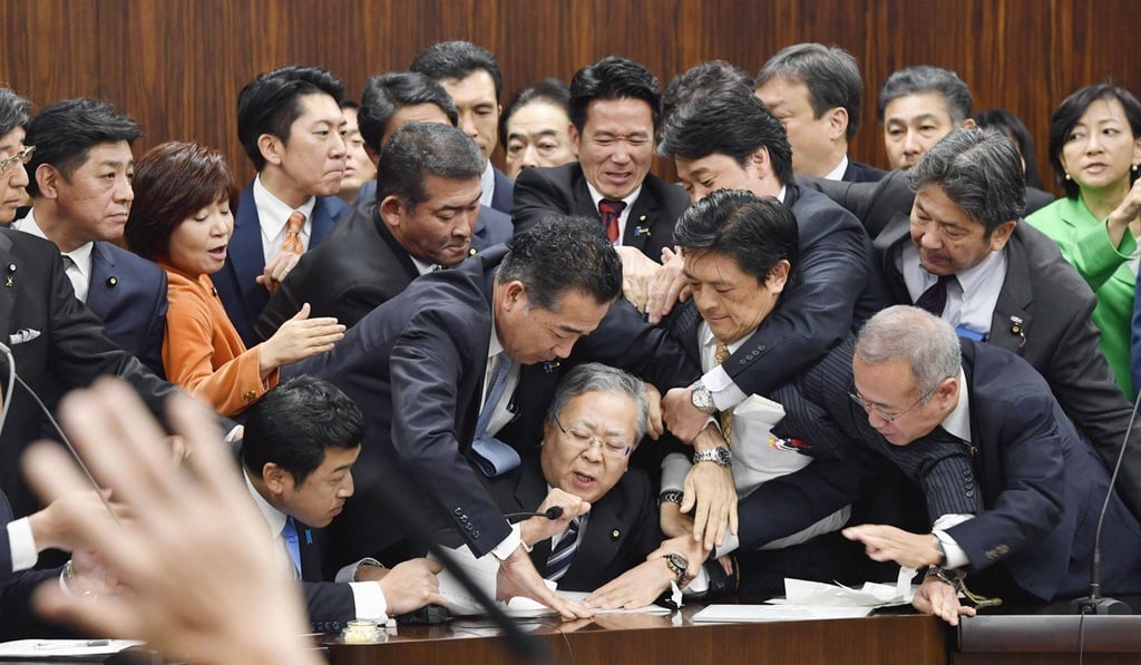 Opposition politicians try to stop Judicial Affairs Committee Chairman Shinichi Yokoyama, bottom centre, from moving to hold a vote for a bill to revise an immigration control law in Tokyo. Photo: AP