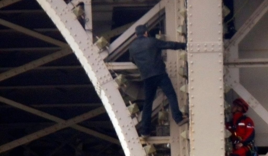 A firefighter (right) approaches an unidentified man, who climbed the Eiffel Tower on Monday. Photo: Reuters