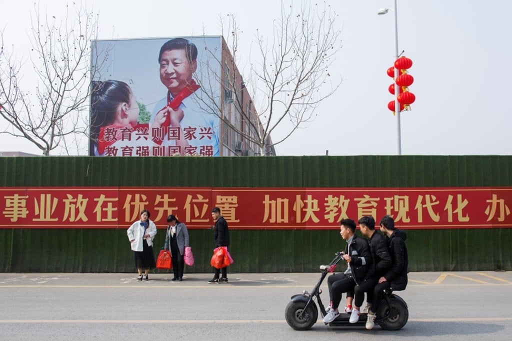 Men ride a scooter past a poster showing Chinese President Xi Jinping on the side of a school building in a newly developed part of Lankao county, in China’s Henan province. Photo: Reuters
