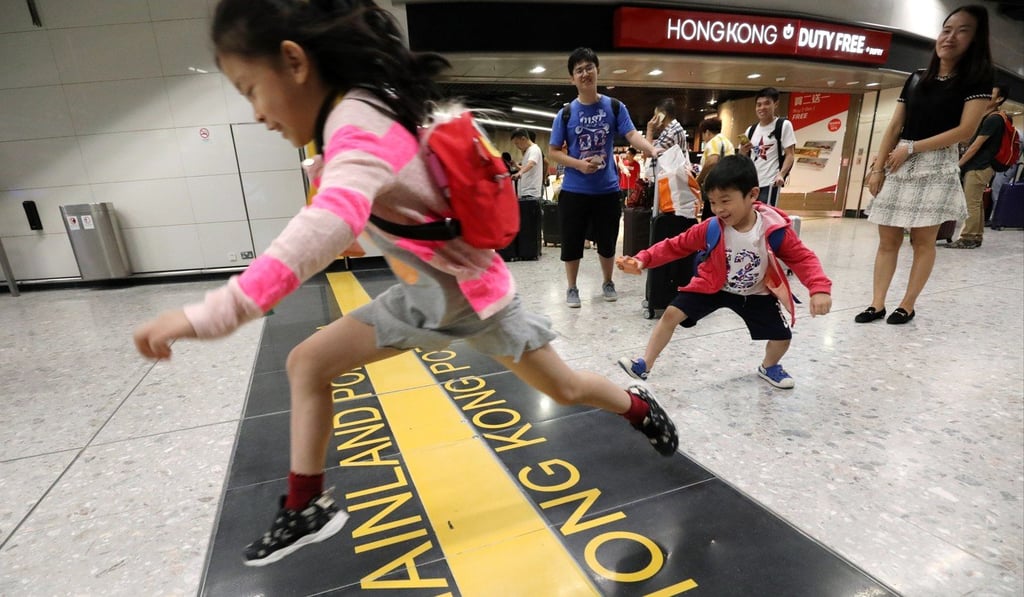 Children jump across the border between Hong Kong and mainland Chinese administrative areas at the West Kowloon High Speed Rail Station on the first operation day of the Express Rail Link in September 2018. Photo: Felix Wong