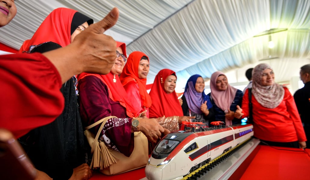 People pose with a train model of the East Coast Rail Link project during a ceremony to break ground in Kuantan, Malaysia. Photo: Xinhua