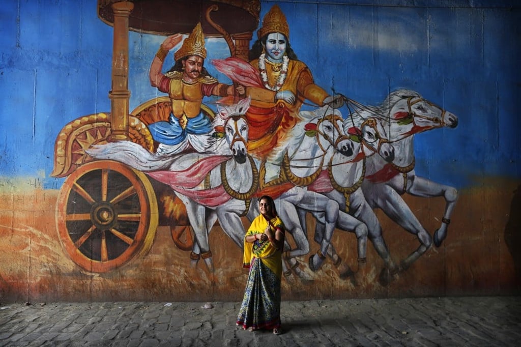 An Indian woman, fresh from voting, stands in front of a mural depicting a scene from the Hindu epic Mahabharata in Prayagraj, Uttar Pradesh. Photo: AP