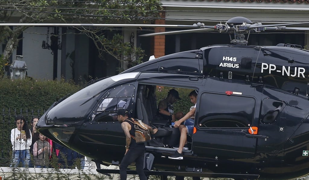 Neymar sits inside his helicopter as teammates Thiago Silva (right) and Daniel Alves (left) exit as they arrive to the Granja Comary training centre. Photo: AP Neymar sits inside his helicopter as teammates Thiago Silva (right) and Daniel Alves (left) exit as they arrive to the Granja Comary training centre. Photo: AP