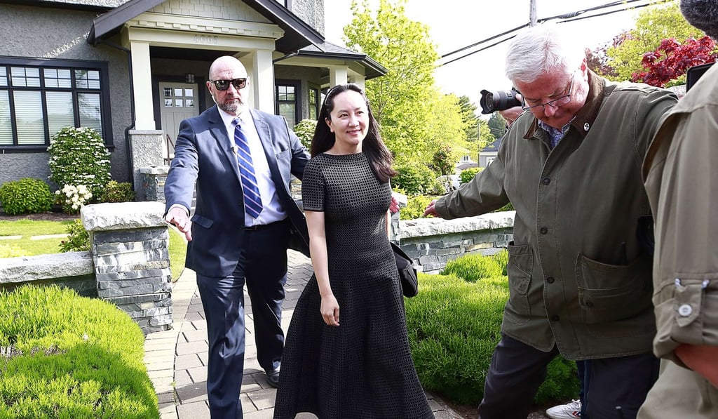Meng is escorted by security as she leaves her home for a court appearance in May. Photo: AFP