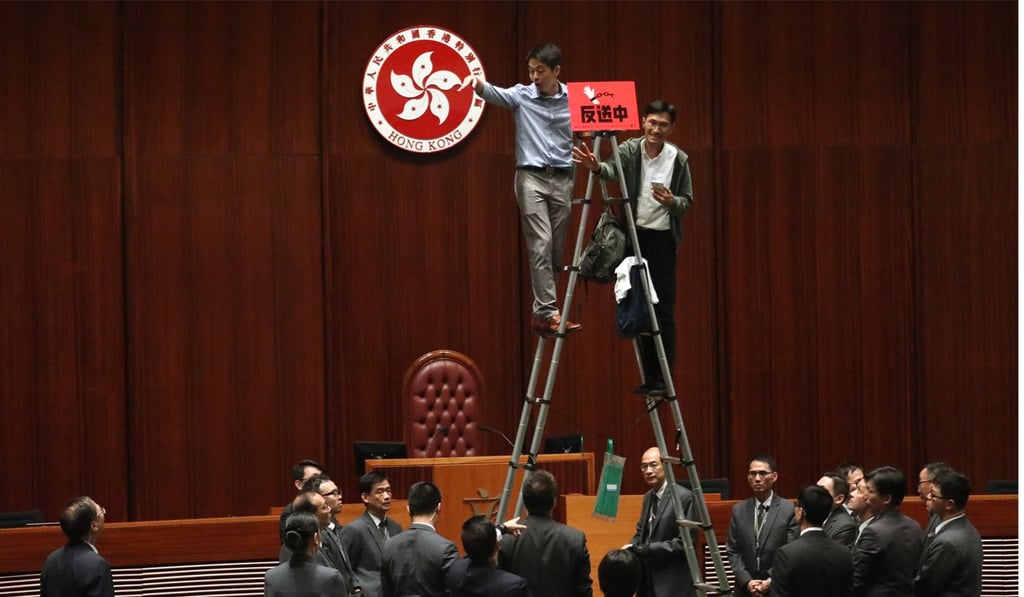Lawmakers Ted Hui (left) and Eddie Chu take to a ladder in the chamber. Photo: Felix Wong