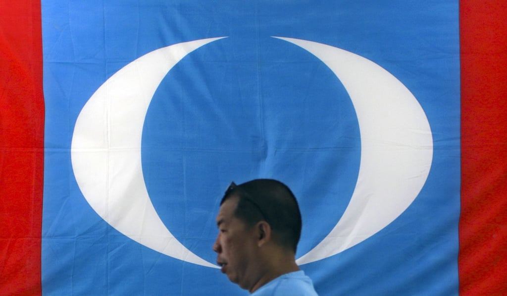 A supporter walks in front of a People’s Justice Party flag in Port Dickson, Malaysia. Photo: EPA
