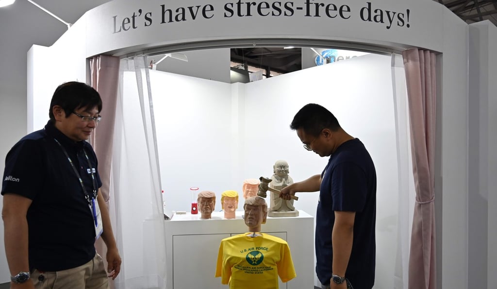 A visitor to the Soliton Systems stand at CES Asia in Shanghai takes aim at the effigy of Donald Trump. Photo: AFP