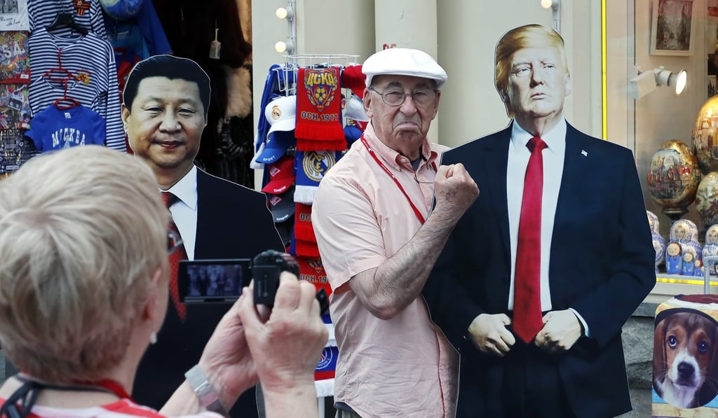 A man has his photo taken with cardboard cut-outs of US President Donald Trump and Chinese President Xi Jinping in Moscow in May. Photo: EPA-EFE
