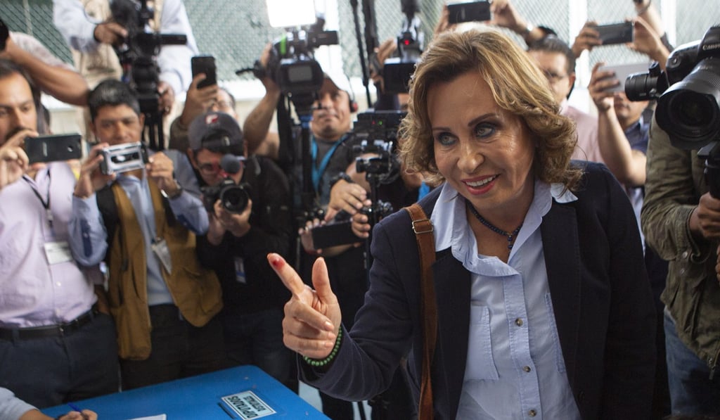 Sandra Torres, presidential candidate from the National Unity of Hope party, shows her ink-stained finger to the press after casting her vote on Sunday. Photo: AP