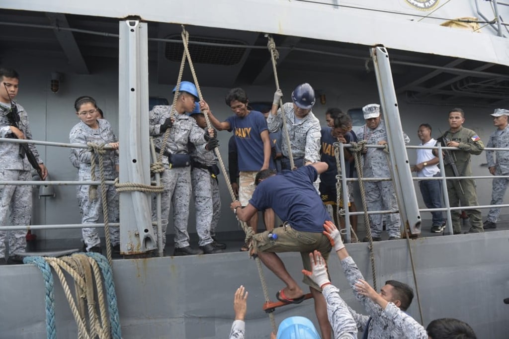 Rescued Filipino fishermen transfer to another ship as they head back to shore. Photo: AP
