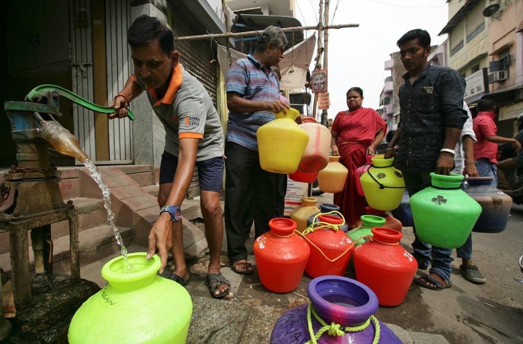 A man uses a hand-pump to fill up a container with drinking water as others wait in a queue on a street in Chennai. Photo: Reuters