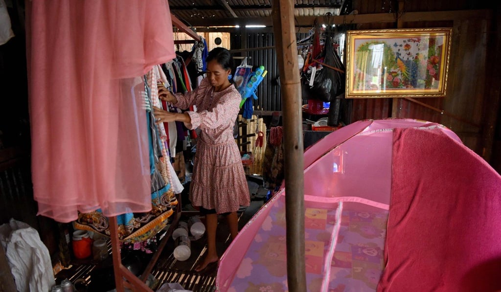 A woman arranging clothes inside her home in front of a grave in Phnom Penh. Photo: AFP