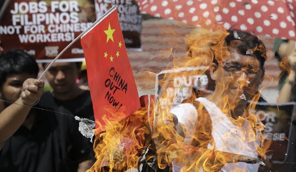 A protester burns mock Chinese flags at Manila's Rizal park, Philippines. Photo: AP A protester burns mock Chinese flags at Manila's Rizal park, Philippines. Photo: AP