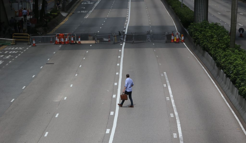 A lone businessman walks on an empty road in Wan Chai after anti-extradition bill protesters blocked Gloucester Road. Photo: Winson Wong A lone businessman walks on an empty road in Wan Chai after anti-extradition bill protesters blocked Gloucester Road. Photo: Winson Wong