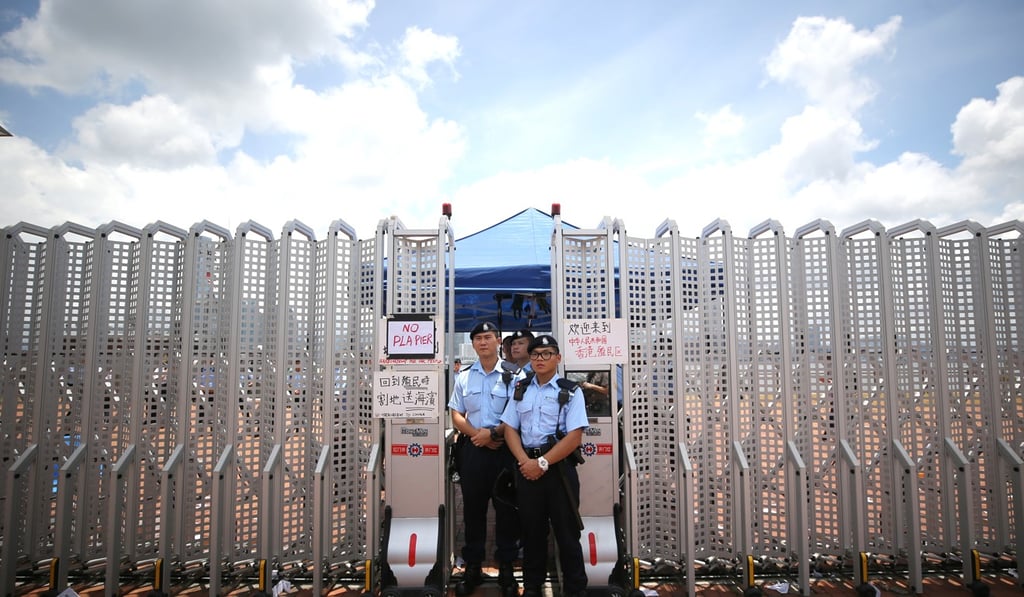 Police stand guard next to new fencing on the site at the harbourfront in Central. Photo: Winson Wong