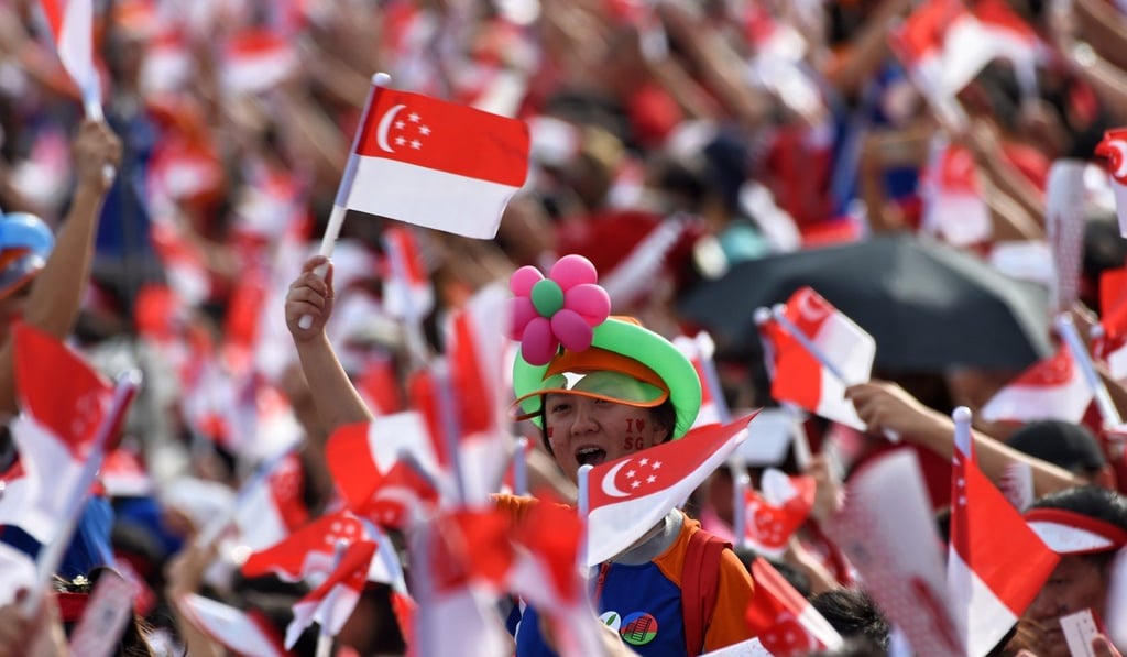 Singaporeans wave national flags during their country’s 53rd National Day parade last year. Photo: AFP