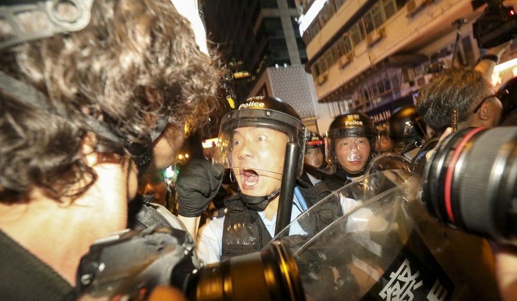 An officer moves a woman out of the way as police clear a street in Mong Kok. Photo: Dickson Lee