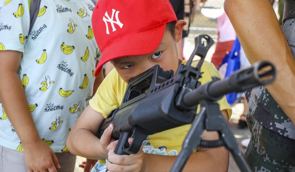 A boy examines a PLA rifle at a base on Stonecutters Island. Photo: Edmond So
